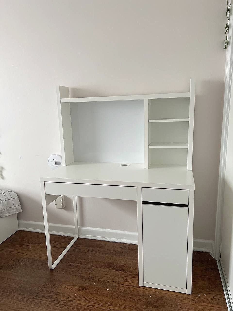 White IKEA desk with hutch and shelves against a white wall.