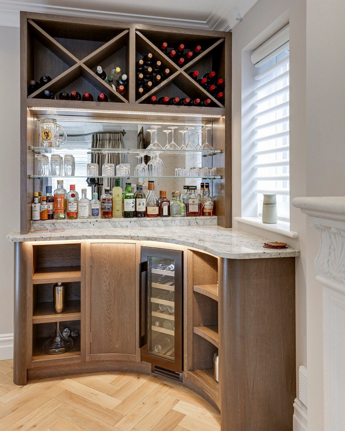 Wooden corner bar cabinet with marble top, wine rack, and integrated wine cooler.