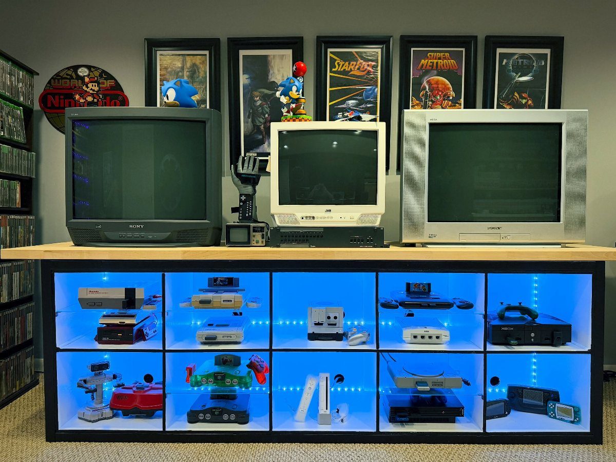Retro gaming setup with CRT televisions and consoles in a blue-lit display cabinet