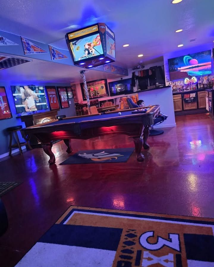 Basement game room with a pool table, arcade machine, and sports bar setup.
