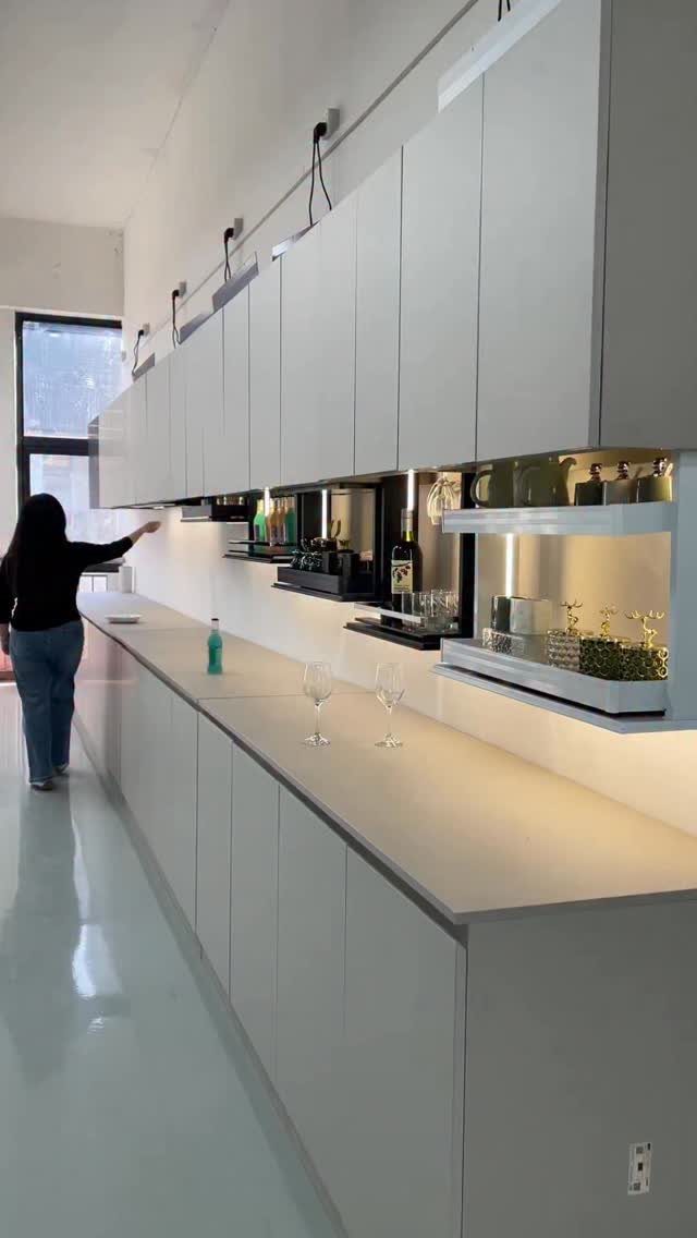 Modern white kitchen with long countertops and low ceilings in a remodeled basement space.
