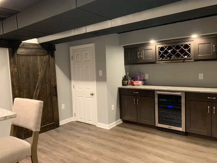 Finished basement with low ceiling beams, wet bar, and rustic wooden barn door.
