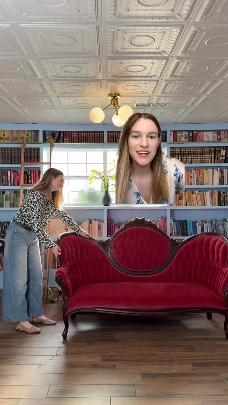 White decorative pressed tin ceiling tiles above a red velvet sofa and bookshelves.