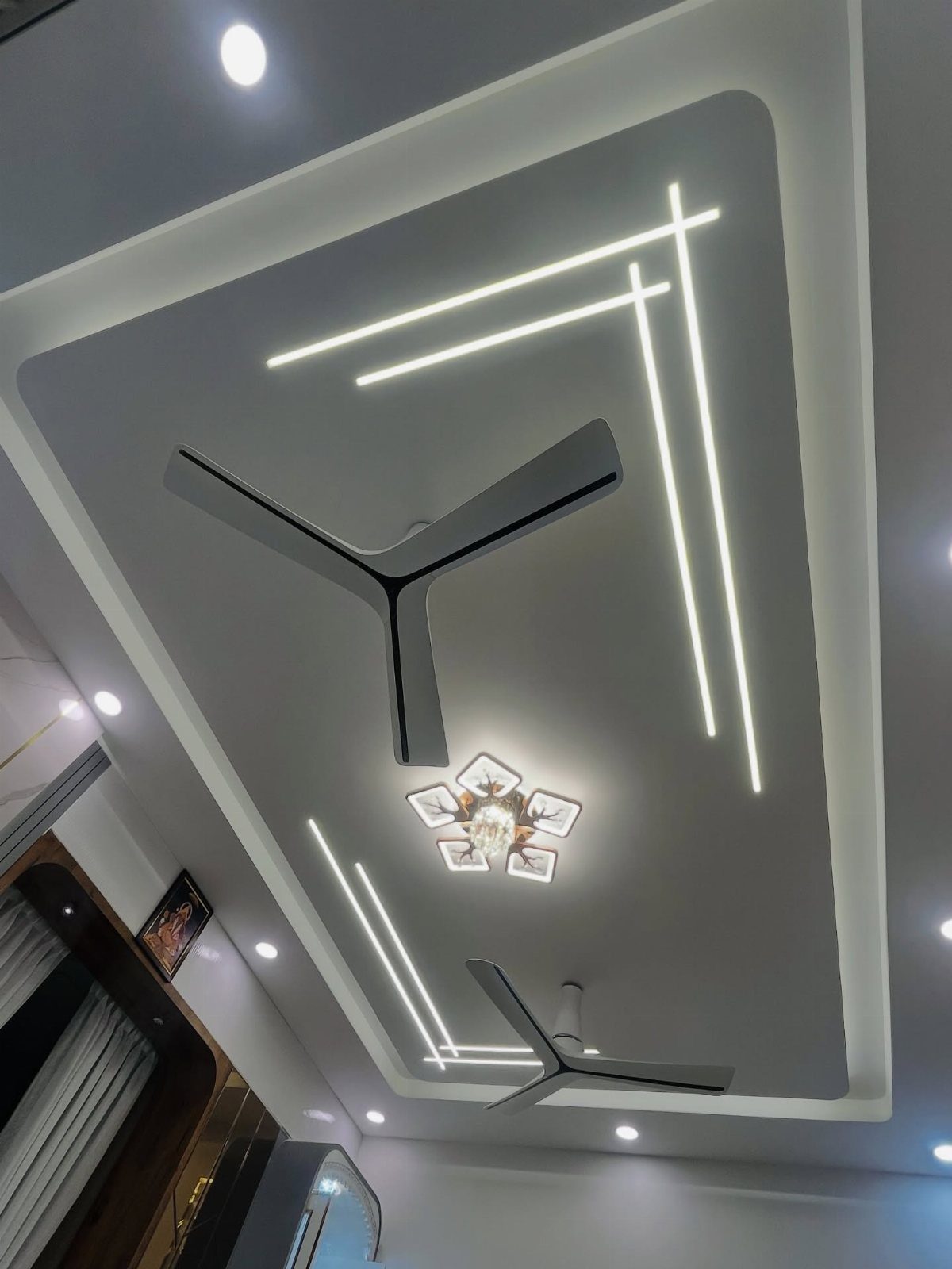 White tray ceiling with linear LED lighting, recessed lights, and two grey fans.