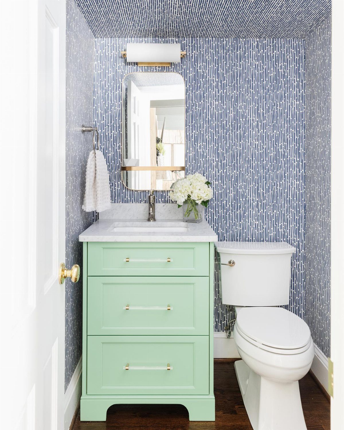 Blue and white vertical striped wallpaper on bathroom walls and ceiling with mint vanity.