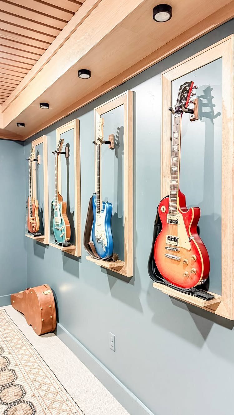 Electric guitars displayed in wooden wall frames against a light blue wall.