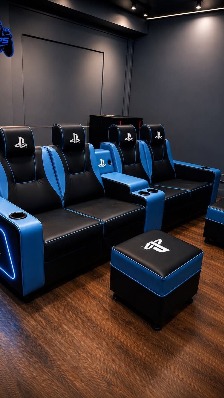 Black and blue PlayStation gaming recliners and ottoman in a dark room.