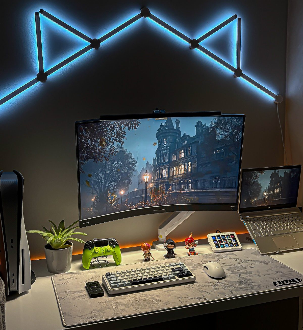 Gaming desk setup with curved monitor, white keyboard, and blue geometric LED wall lights.