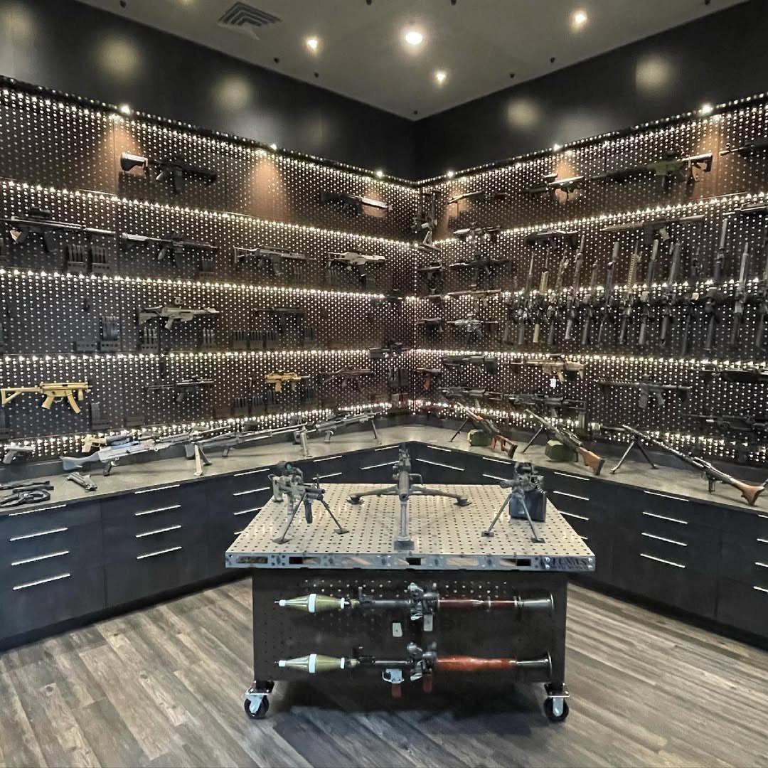 Custom firearm cabinetry and pegboard walls displaying a large collection of rifles and guns.