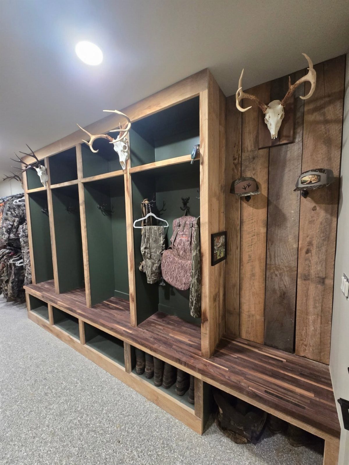 Custom wooden hunting gear storage unit with camouflage clothing and deer trophy mount.
