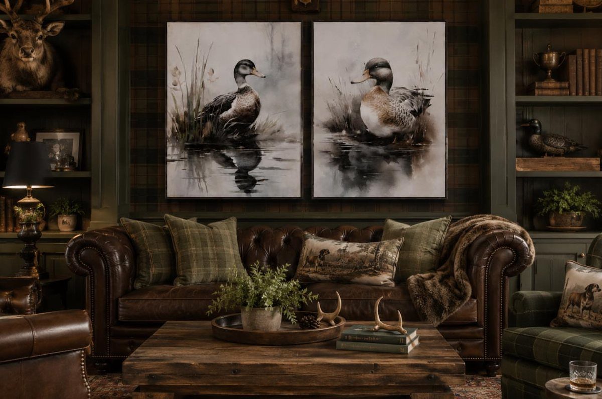 Two large duck paintings hanging above a brown leather sofa in a rustic room.