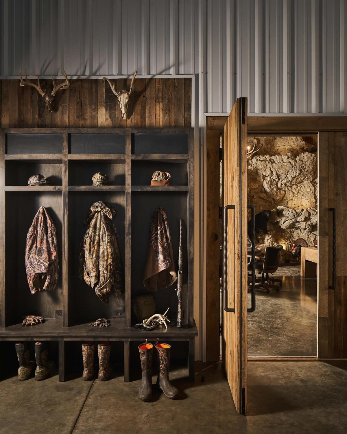 Rustic mudroom with animal hides, boots, and deer skulls mounted on wooden walls.