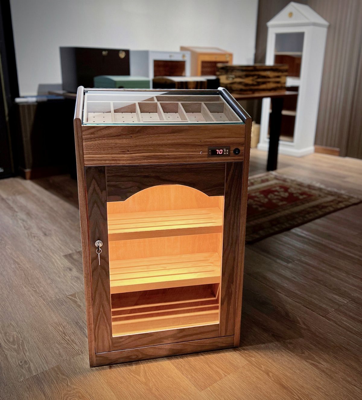 11 Man Cave Must Haves for Your Space 9 Wooden cigar humidor cabinet with glass top and illuminated interior shelves on wooden floor.