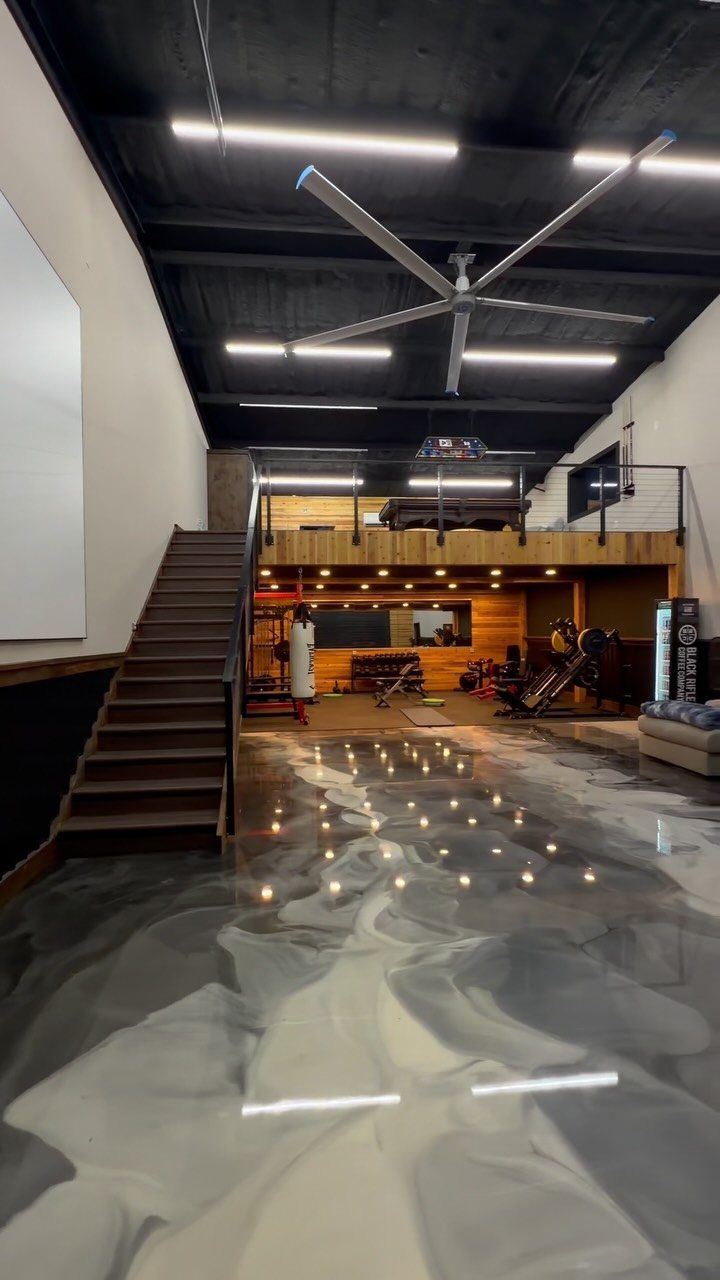 11 Man Cave Must Haves for Your Space 11 Modern man cave with a glossy epoxy floor and gym equipment in the background.