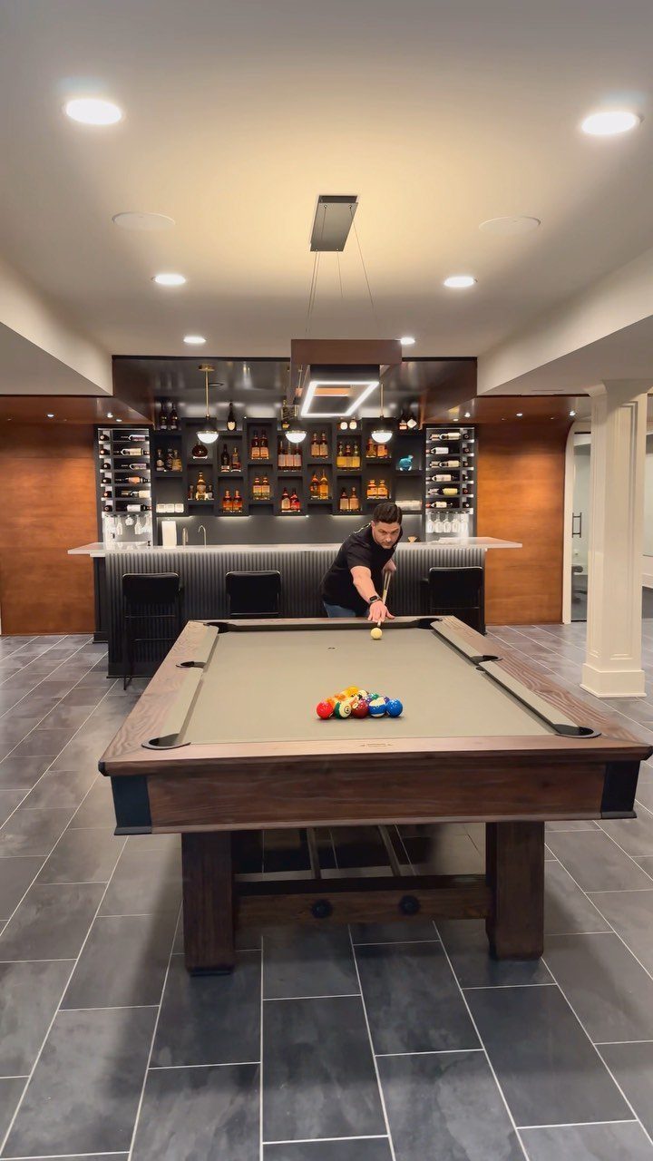 11 Man Cave Must Haves for Your Space 1 Man playing pool on a wooden table in a modern basement man cave