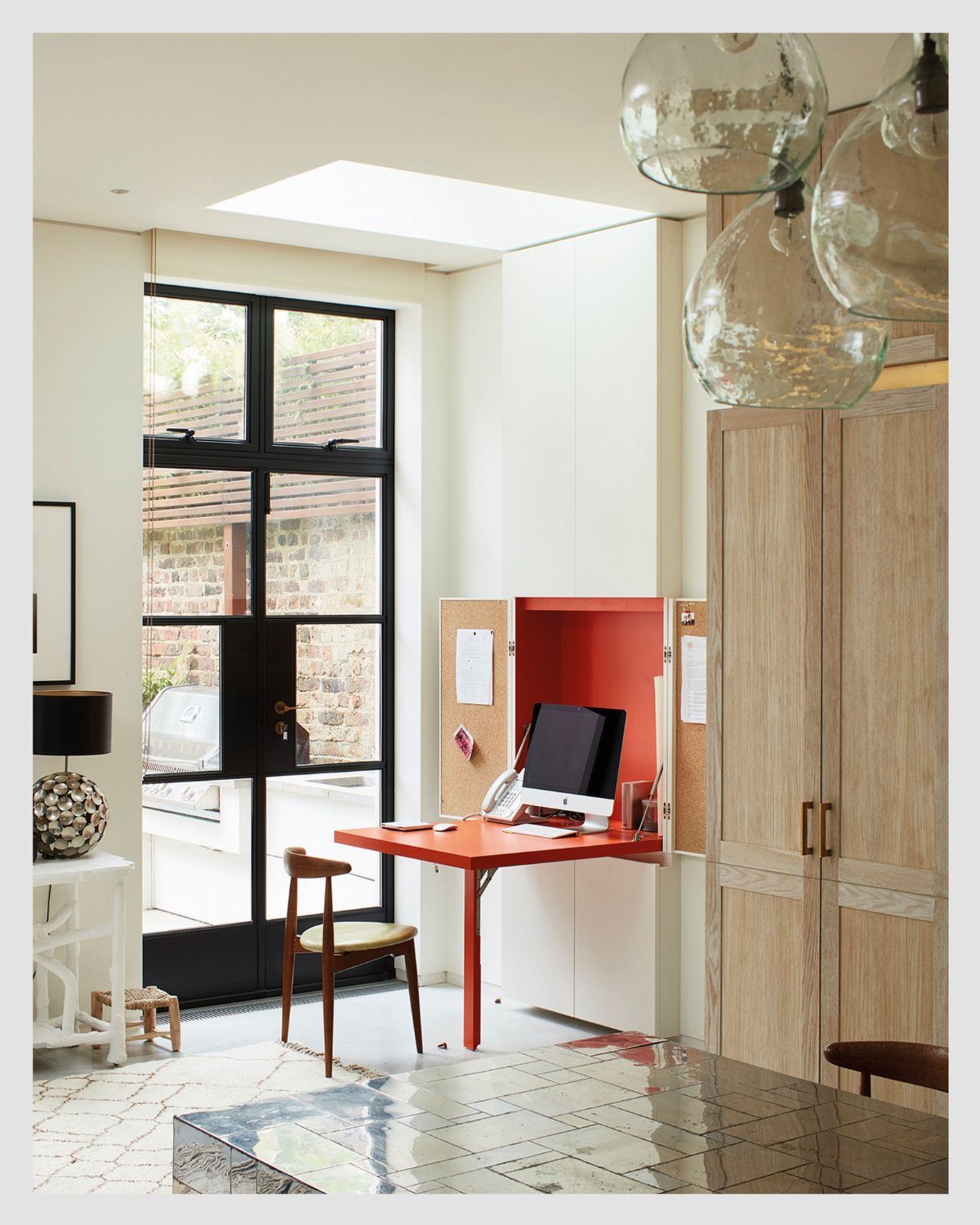 14 Office Decorating Ideas for Work to Refresh Your Space 10 Red fold-down wall desk with a computer monitor and wooden chair in bright room.