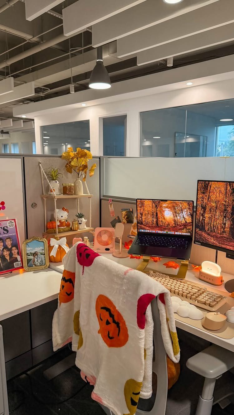 14 Office Decorating Ideas for Work to Refresh Your Space 13 Decorated office cubicle with autumn-themed pumpkins, yellow flowers, and a pumpkin-patterned blanket.