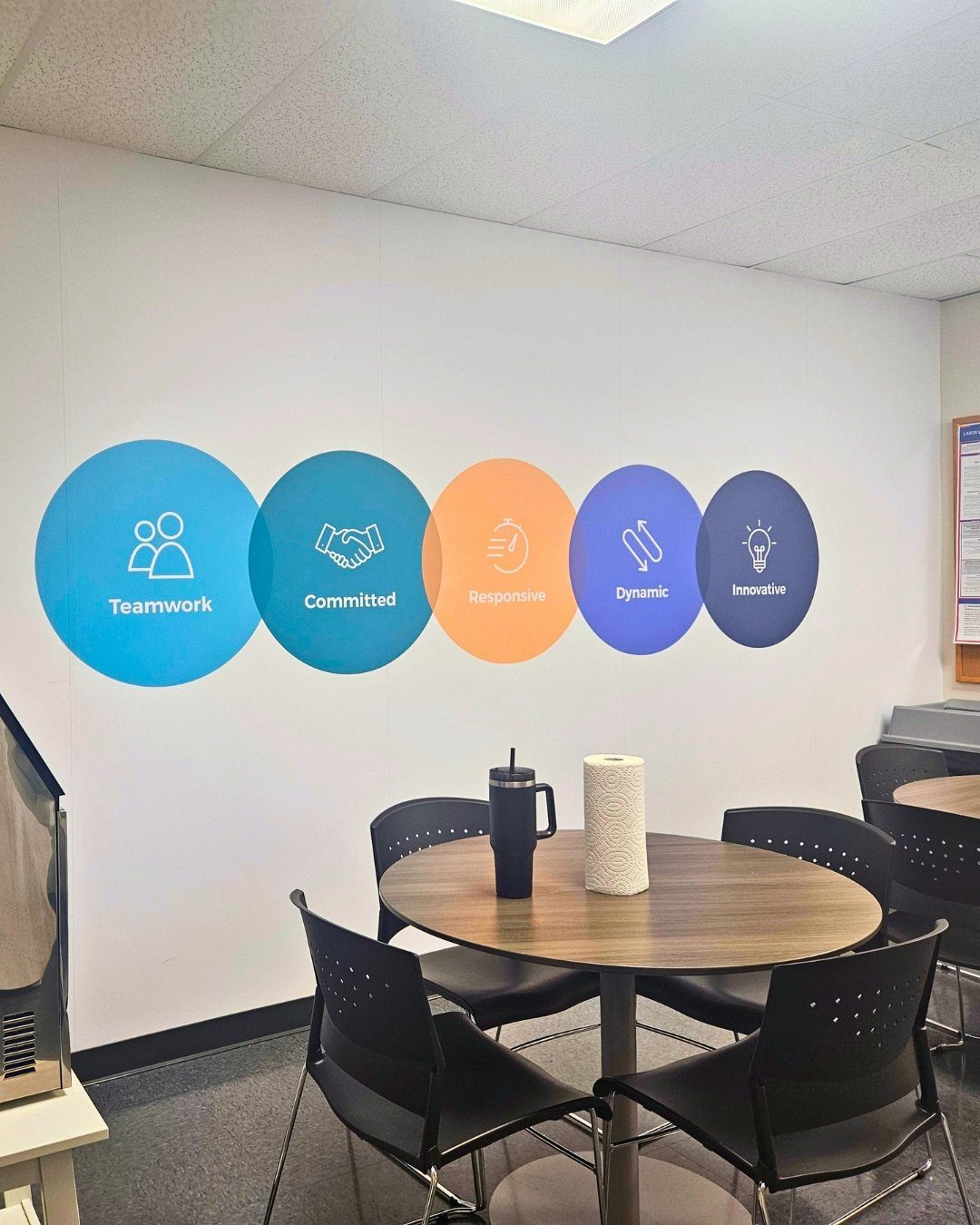 14 Office Decorating Ideas for Work to Refresh Your Space 5 Colorful circular wall decals with corporate values on a white office wall.