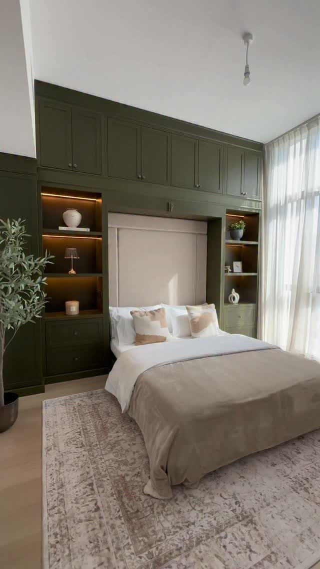 Murphy bed integrated into olive green built-in cabinetry with shelving and overhead storage.