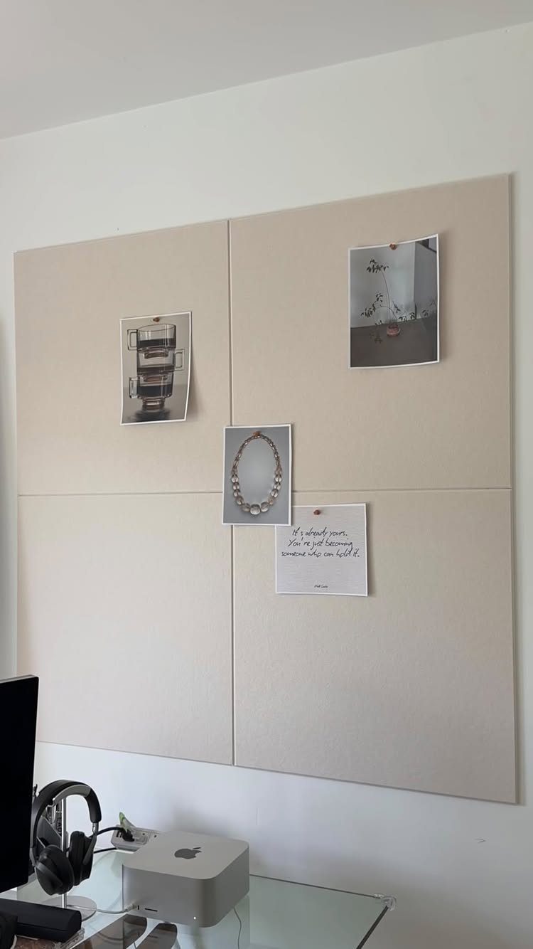 Beige fabric mood board with pinned photos and notes above a white computer desk.