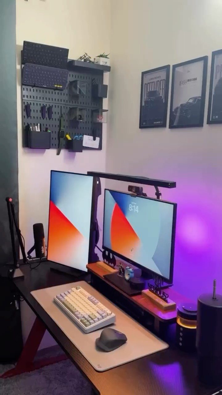 Home office setup with dual monitors, white keyboard, and black wall pegboard.