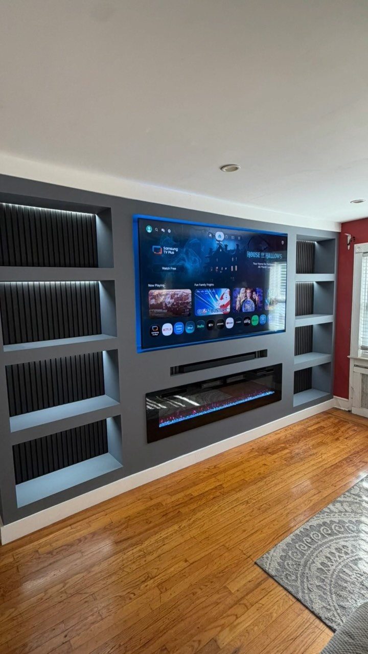 Recessed TV and linear fireplace set into a dark grey media wall with shelving.