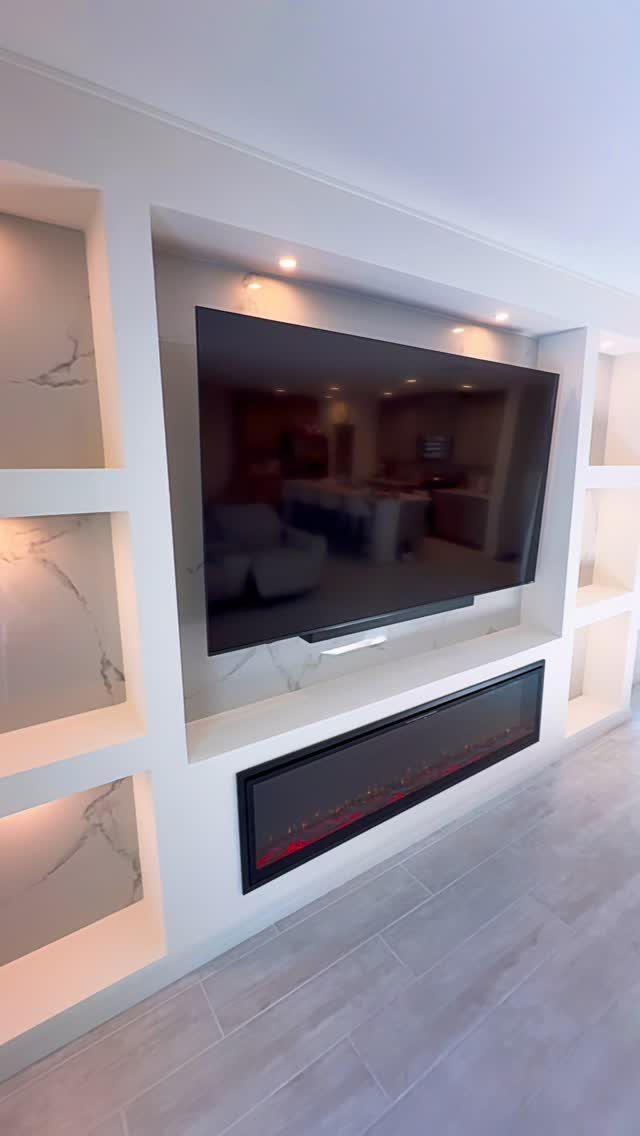 White recessed TV wall with a deep opening, linear fireplace, and marble niches.
