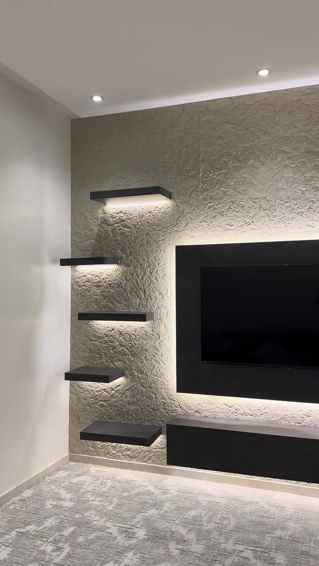 Textured stone wall with a mounted black TV and illuminated floating black shelves.