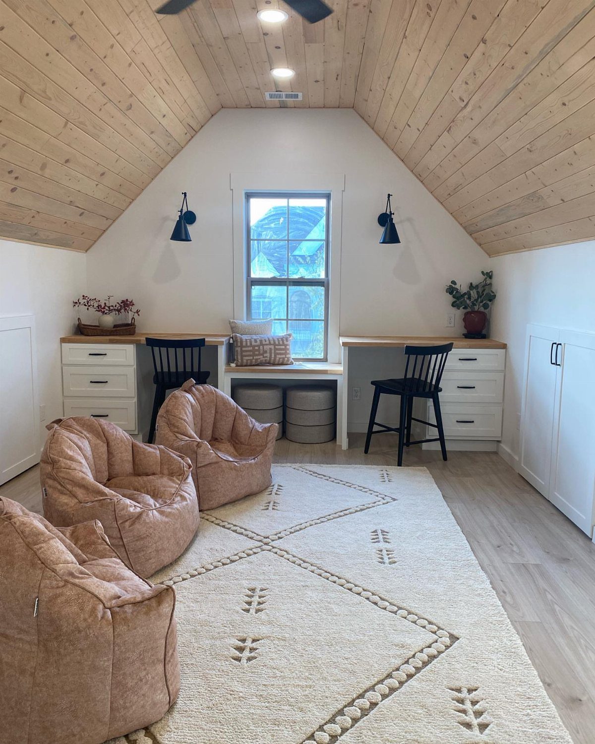 White built-in knee-wall storage drawers flanking a window seat in a bright attic room.