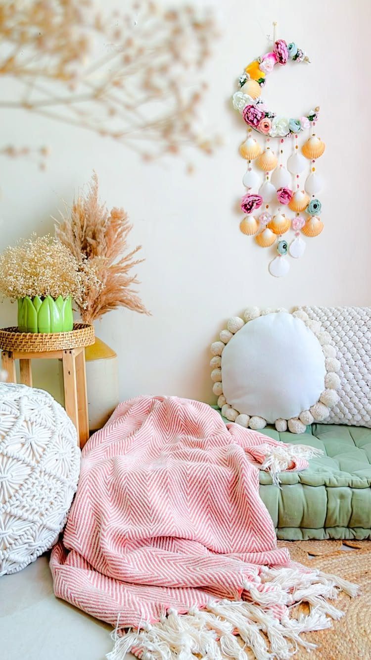 Green tufted floor mattress with pink striped blanket and floral moon wall decor.