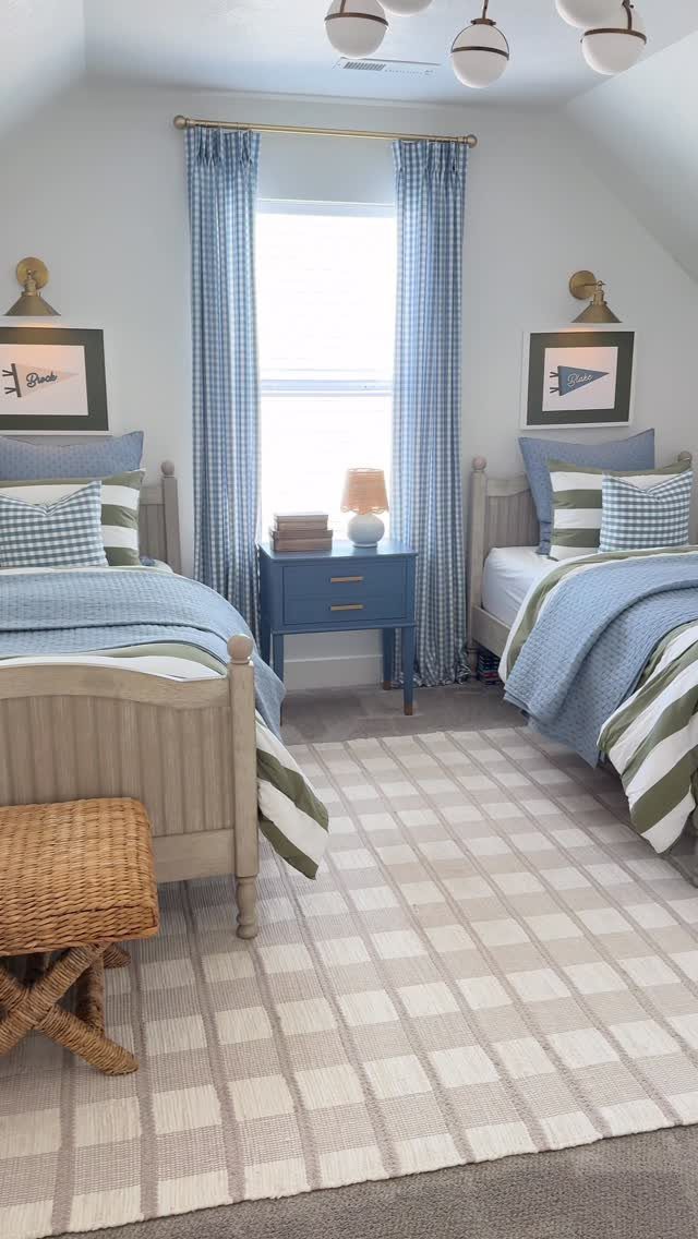 Two twin beds with blue bedding in a small attic bedroom with sloped ceilings.
