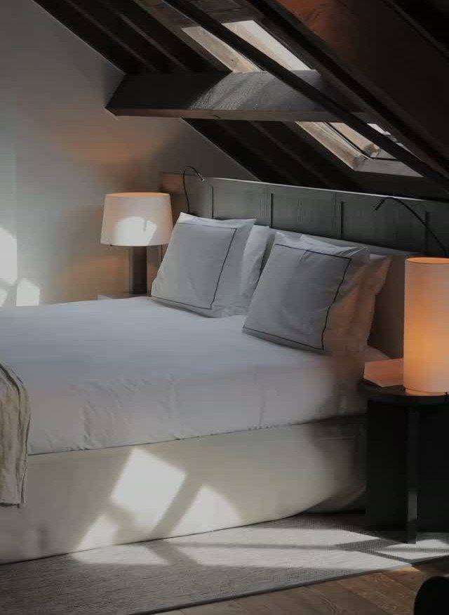 Attic bedroom with dark unpainted exposed wooden beams and a bright skylight.