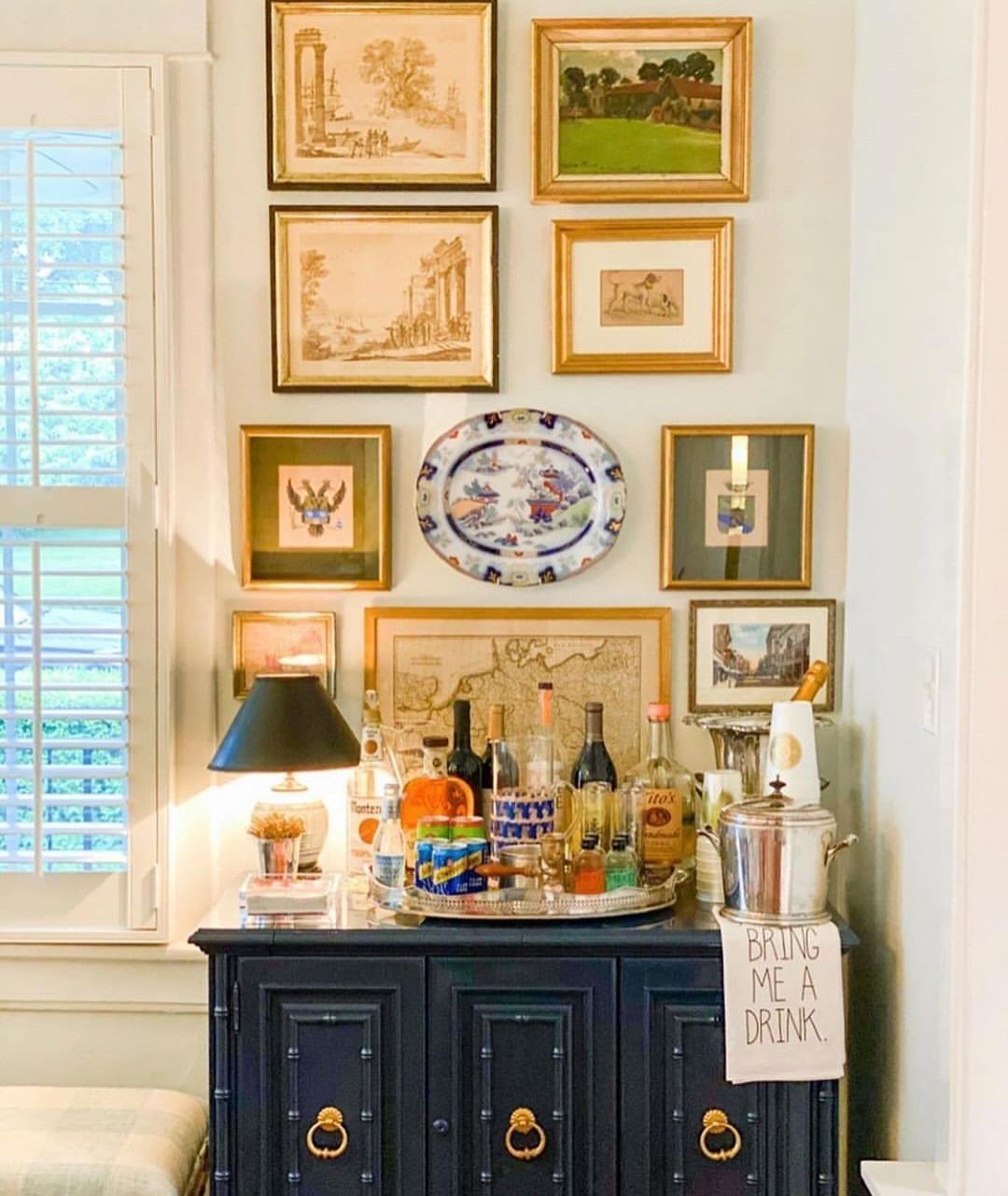 18 Small Bars for Home That Fit Any Space 18 Dark blue home bar cabinet with liquor bottles and framed art on the wall
