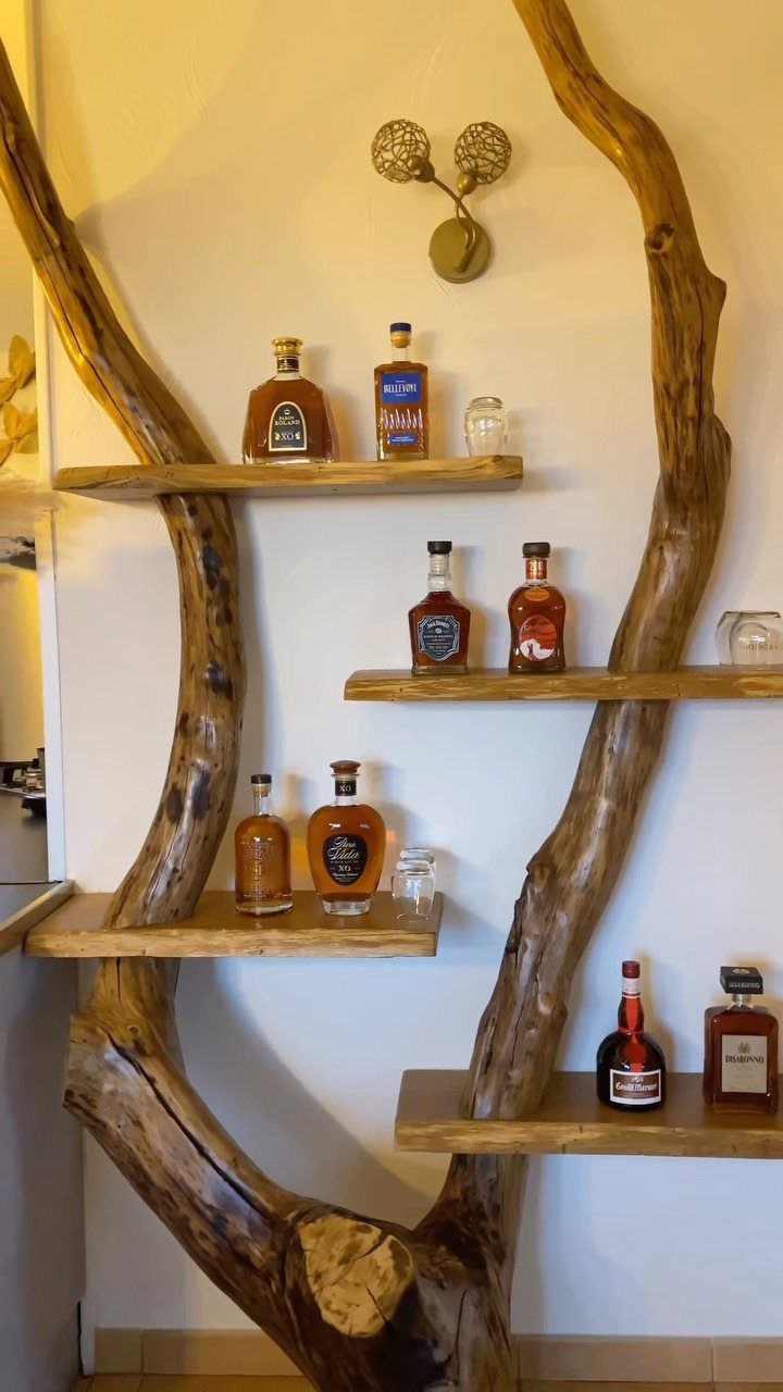 18 Small Bars for Home That Fit Any Space 17 Rustic home bar with liquor bottles on wooden shelves supported by natural branches