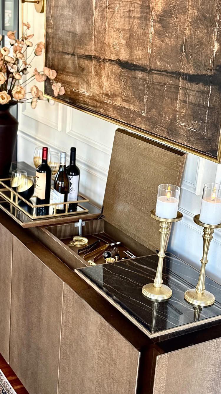 18 Small Bars for Home That Fit Any Space 6 Brown wood-paneled bar cabinet with black marble top, wine bottles, and gold candles.