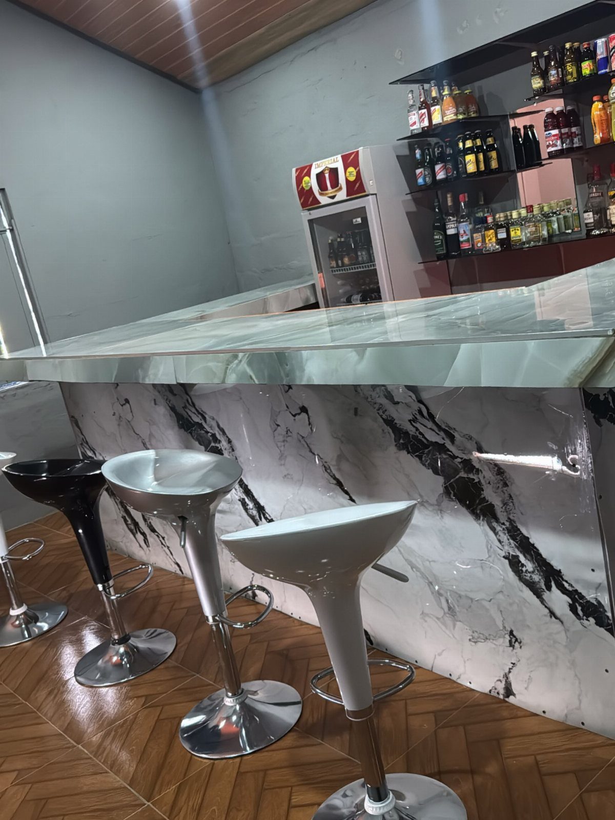 18 Small Bars for Home That Fit Any Space 2 Marble topped home bar with modern bar stools and liquor shelves in background