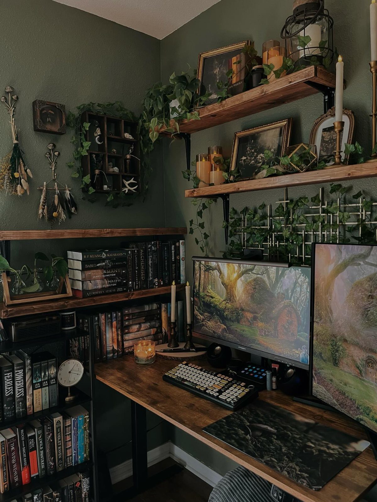 Gaming desk with dual monitors and wooden shelves decorated with trailing green ivy plants.
