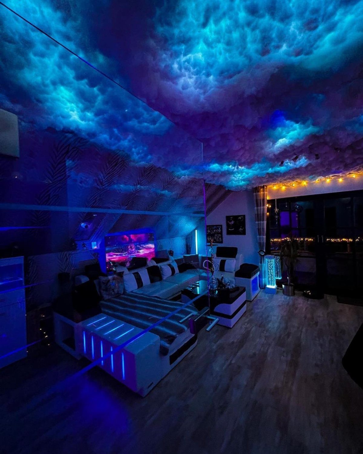 Gaming room with blue LED cloud ceiling and white modular light-up sofa.