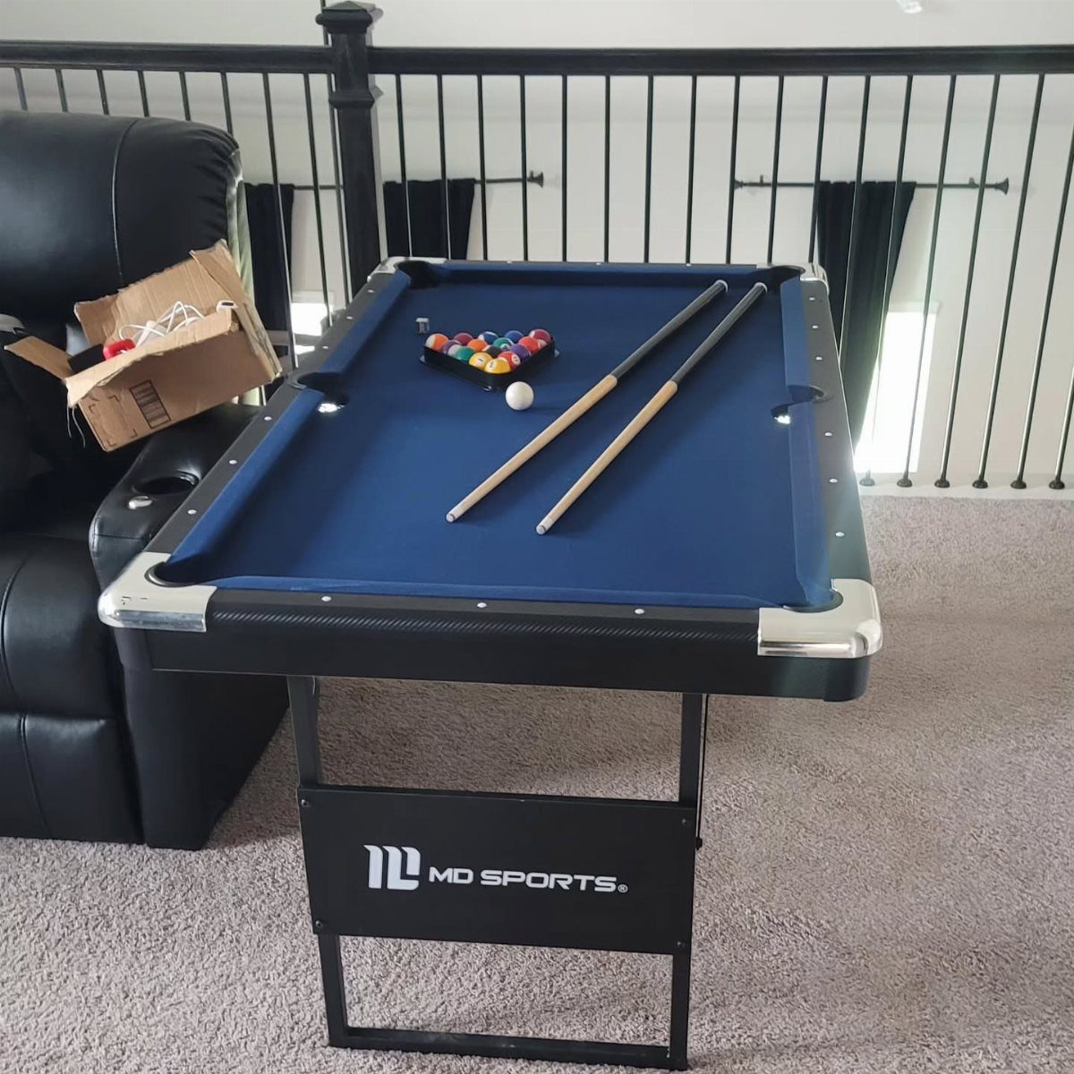 Compact blue pool table with cues and balls in a home setting.