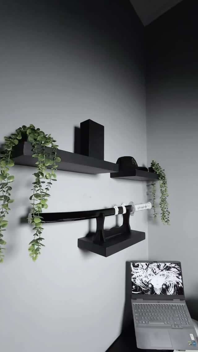 Black floating shelves on a grey wall with trailing plants and a katana.