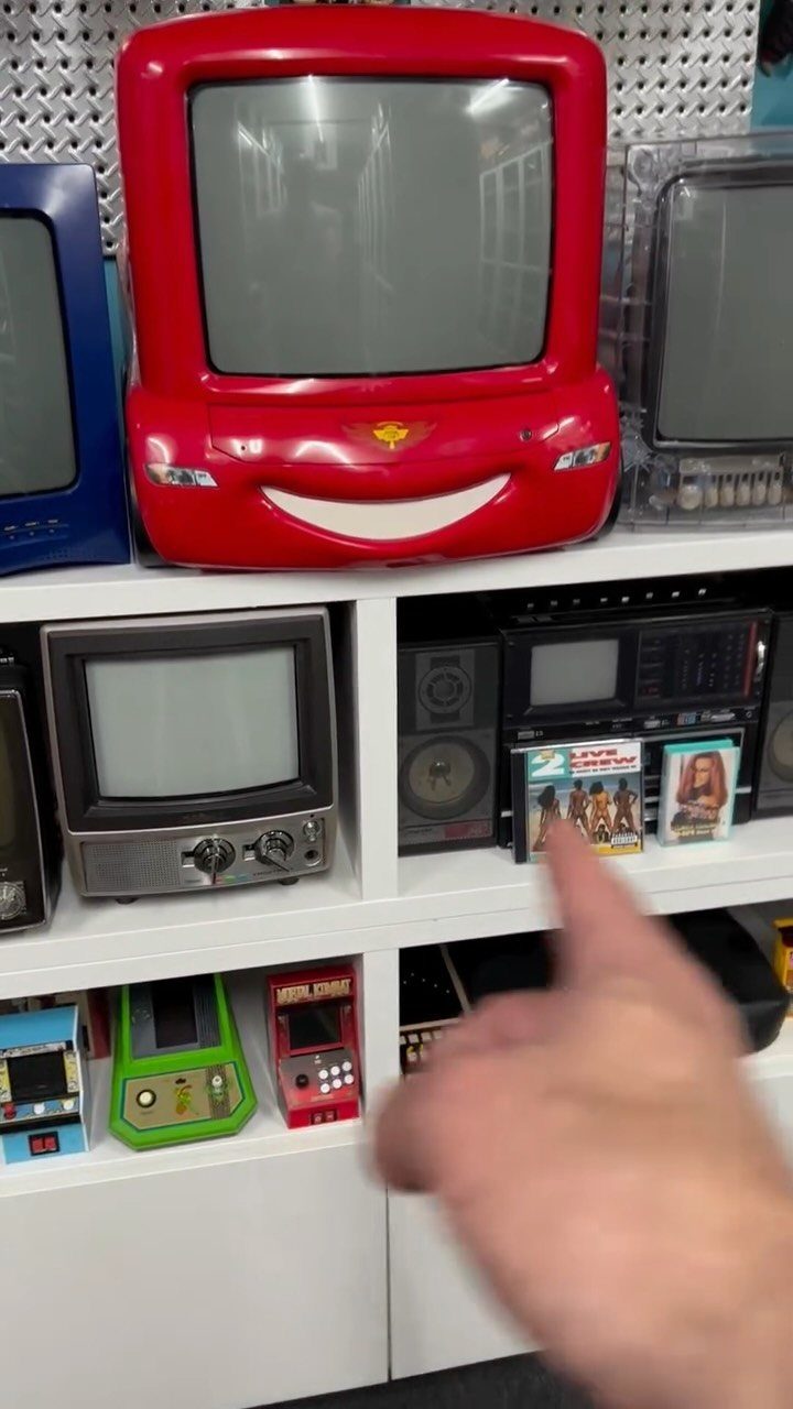 White KALLAX shelving unit displaying vintage televisions and handheld gaming consoles.