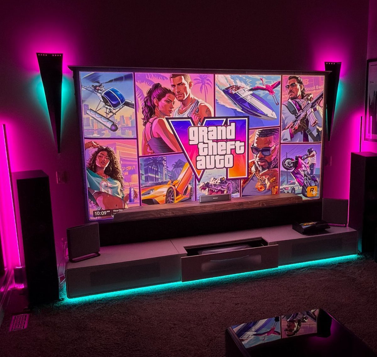 Gaming setup with Grand Theft Auto screen and vibrant pink and cyan neon lighting.