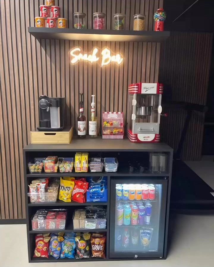 Home snack bar with neon sign, popcorn machine, and snacks in a cinema room.