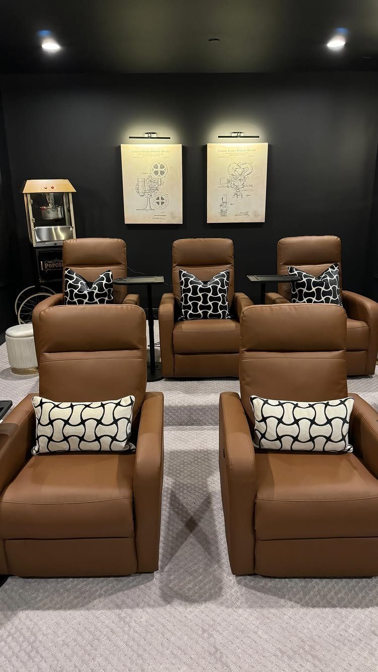 Brown leather recliners with patterned pillows in a dark home cinema room.