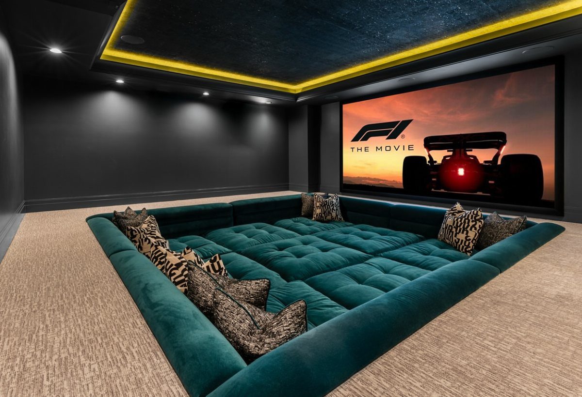 Modern home cinema with a large screen and a giant teal velvet pit sofa.