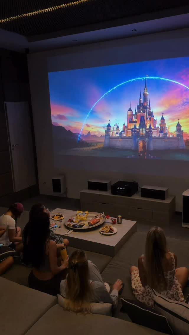 Home cinema room with people on a sectional sofa watching a projected movie.