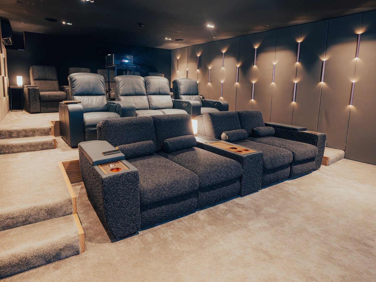 Tiered home cinema seating with grey fabric and leather recliners in a dark room.