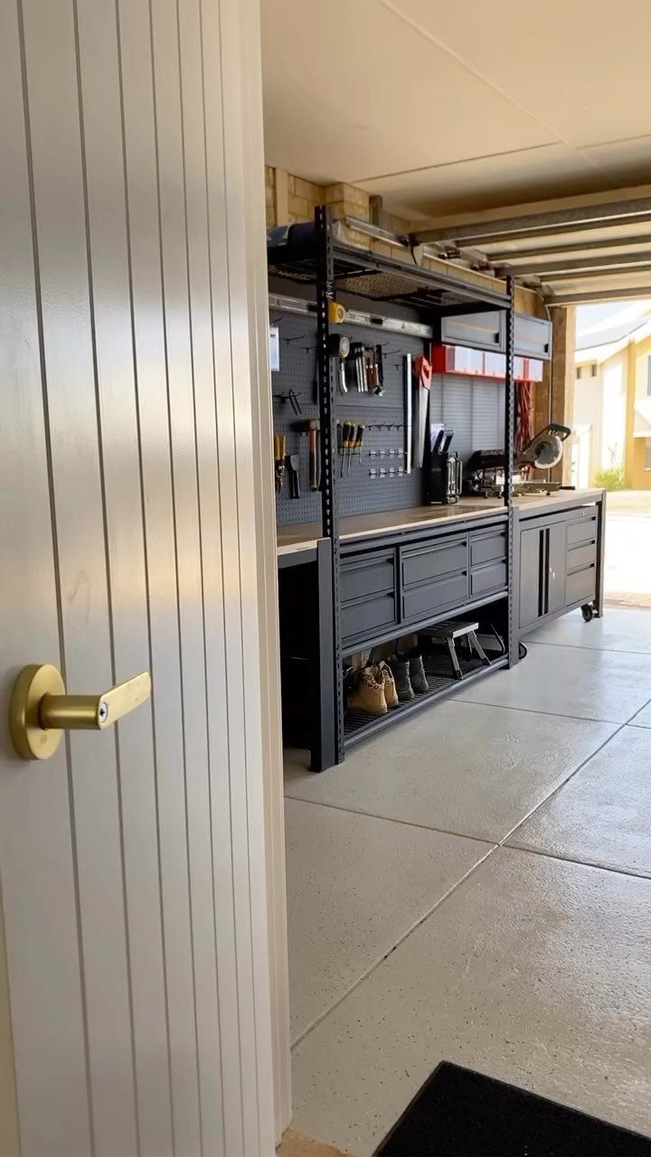 Dark grey metal workbench with drawers and pegboard storage in a clean garage.