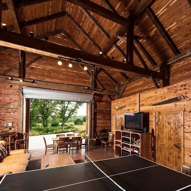 Rustic wooden man cave with ping pong table, leather sofa, and dining area.