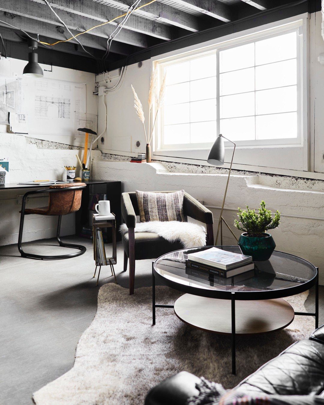 Black painted exposed ceiling with beams and pipes in an industrial living space.